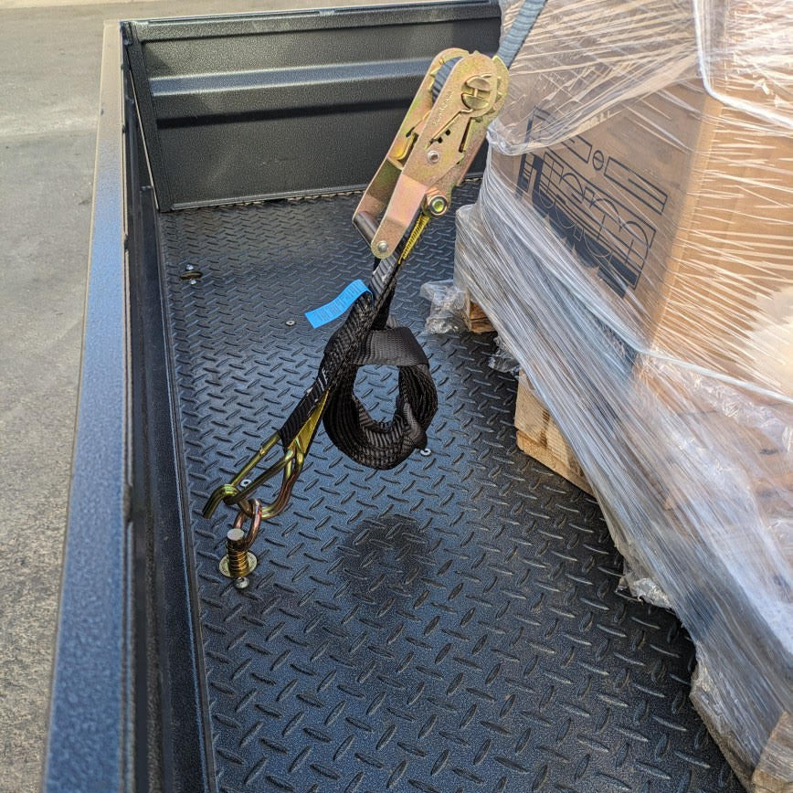 Ratchet strap hooked to a TurnLock tie-down point in a ute tray, securing a pallet